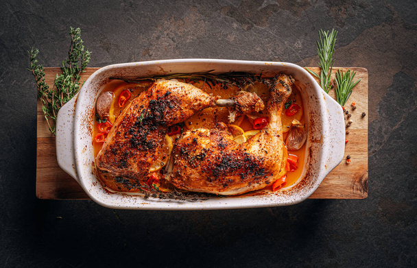 roasted fried turkey duck thighs, rubbed with spices and salt, on a baking sheet, with oranges, lemons, garlic, rosemary, thyme and olive oil. the concept of a healthy and tasty dinner for two. - Fotó, kép