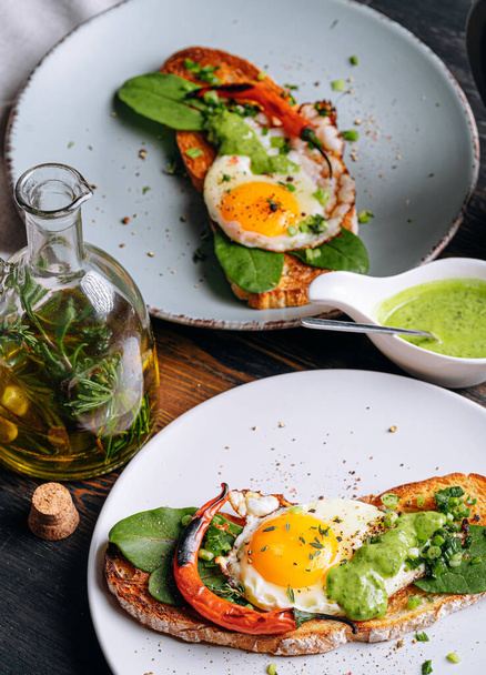 delicious and appetizing bruschetta with fried eggs and herbs for breakfast - Фото, изображение