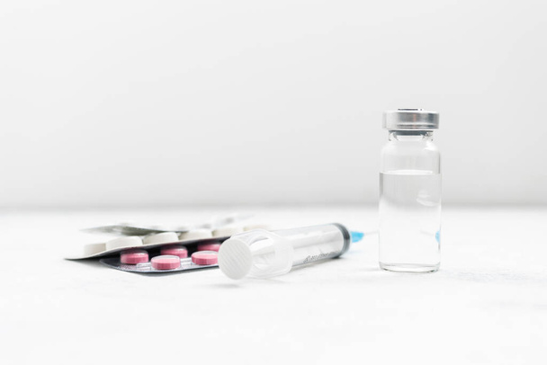 Medische spuit, medicijnpillen en glazen injectieflacon op witte achtergrond, medicijn en behandelingsconcept. - Foto, afbeelding