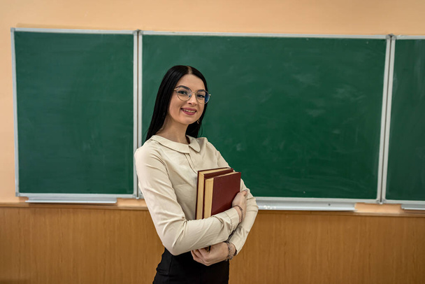 Счастливая молодая учительница возле доски в классе школы. концепция образования - Фото, изображение