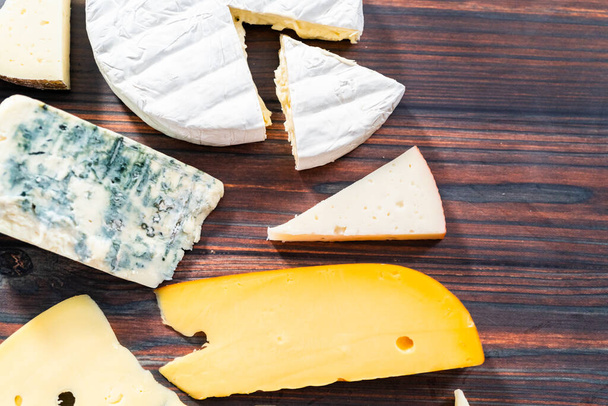 Různé velké gurmánské sýrové klíny na tmavém dřevěném pozadí. - Fotografie, Obrázek