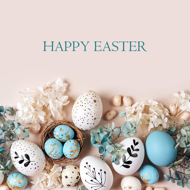 Easter eggs with sweets and flowers on beige. Happy Easter concept. White and blue eggs and cute nest with candy  - Foto, immagini