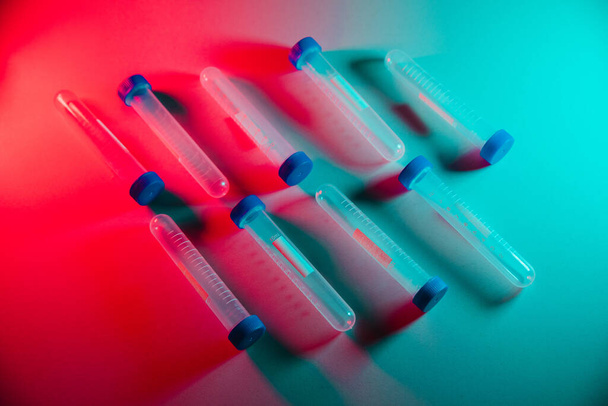 Testbuizen op een tafel in neonverlichting. Geneeskunde en biologisch of chemisch onderzoek - Foto, afbeelding