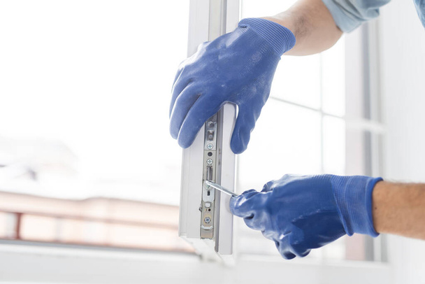 A gloved worker adjusts the installed plastic door - Foto, afbeelding