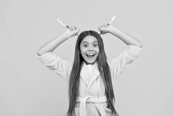 Смешная счастливая девочка-подросток дома махровый халат держать зубную щетку, как рога дьявола, повседневной рутины - Фото, изображение