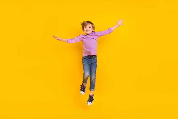 Full size photo of cheerful playful charming boy jumping up waiting summer vacation isolated on yellow color background - Fotografie, Obrázek