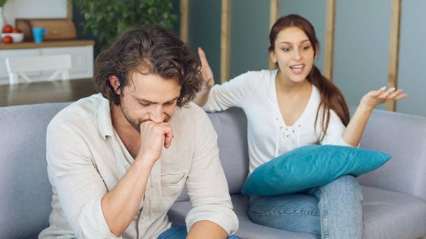 Couple Quarreling Sitting on the Couch at Home, Boyfriend Screams Accusing Girlfriend. Relationship Problems by Reason of Disagreement. - Фото, изображение