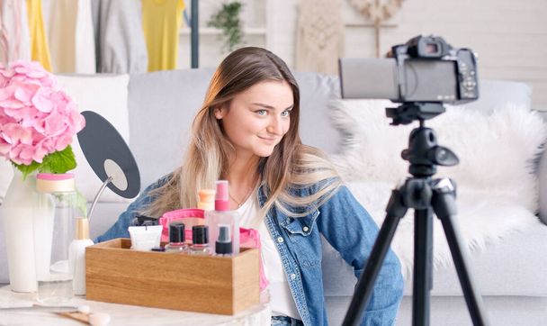 Una giovane donna, un blogger di bellezza gira il suo video blog sulla bellezza. Recensione di Cosmetics Live at Home. Influenzatori di bellezza di nuova generazione - Foto, immagini