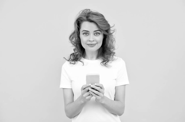 笑顔の赤毛の女性は、スマートフォンでチャットや黄色の背景にオンラインショッピングを作る、ブログ - 写真・画像