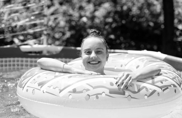 Idealny do pokonania letnich upałów. Szczęśliwa dziewczyna pływa w basenie z pączkami. Dzień zimnego basenu. Wakacje - Zdjęcie, obraz
