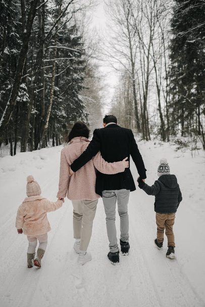 A married couple walks through the winter forest with two children. High quality photo - Photo, image