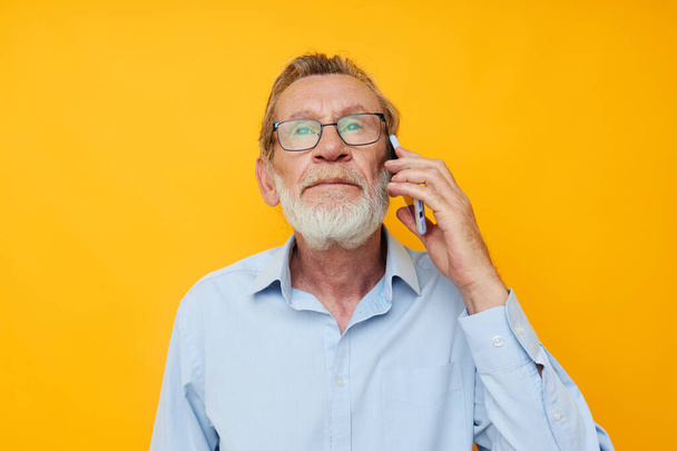 old man gray beard with glasses talking on the phone isolated background - Foto, afbeelding