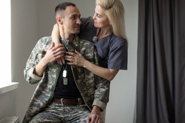 Bakıcı kadın hemşire, hastanede onunla konuşurken el ele tutuşup, askerî kocasına destek oluyor. - Fotoğraf, Görsel
