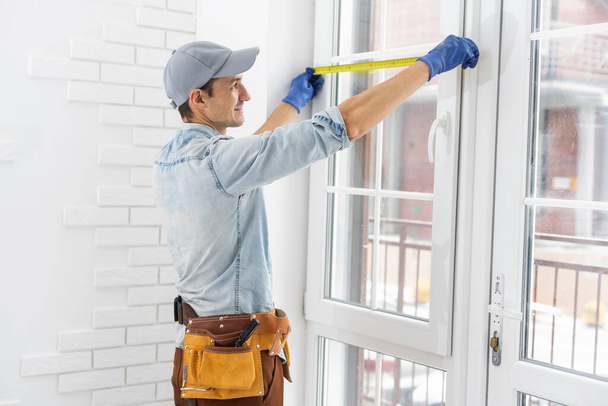 El trabajador instala y comprueba la ventana en la casa - Foto, Imagen
