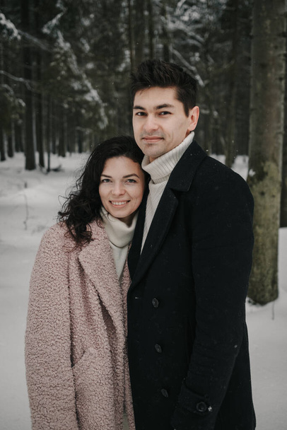 A young couple looks into the camera against the background of a winter forest - Photo, Image