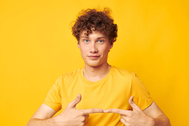 portrait of a young curly man yellow t-shirt fashion hand gestures isolated background unaltered - Photo, image