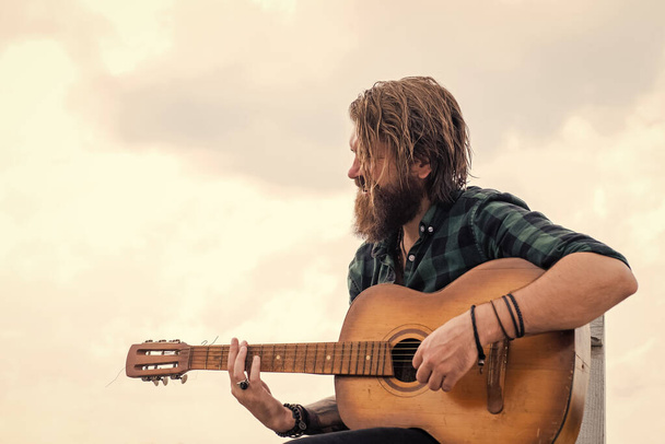 way to relax. brutal handsome man with moustache play guitar. mature musician and singer. casual styled guitarist. modern looking bearded hipster with acoustic guitar. music concept - Photo, image