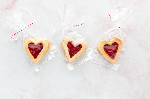 Galletas Linzer en forma de corazón envueltas en paquetes de celofán, para el Día de San Valentín. - Foto, imagen