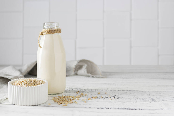 Barley milk in a glass bottle on light wooden boards - Foto, Bild
