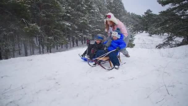 сім'я в зимовому лісі, мати з усміхненими дітьми насолоджується слайдом і снігом під час активних свят
 - Кадри, відео