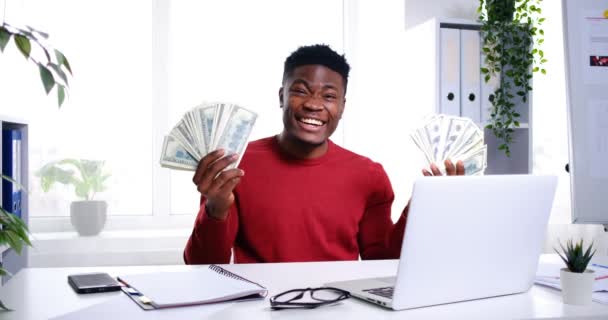 Emocionado hombre de negocios afroamericano agitando fan de billetes de efectivo en dólares - Metraje, vídeo