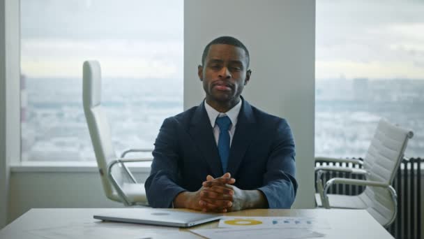 Молодой афроамериканский бизнесмен смотрит в камеру в офисе - Кадры, видео