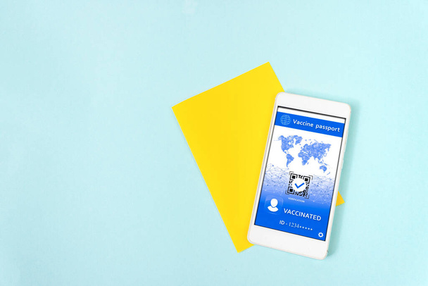 Gelber Zettel mit digitalem COVID-Zertifikat auf einem Smartphone-Bildschirm auf blauem Hintergrund - Foto, Bild