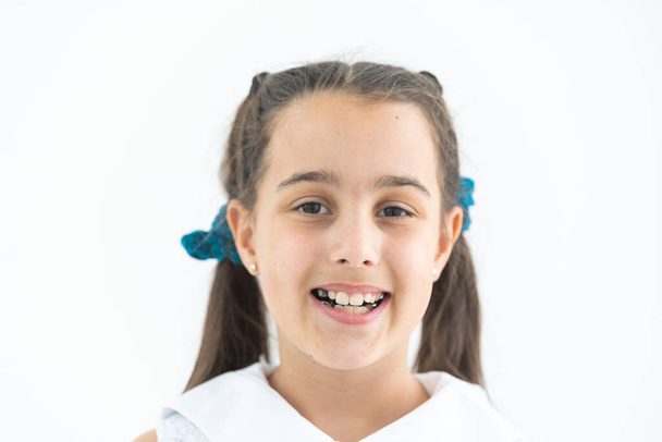 Маленькая девочка показывает свои здоровые зубы в стоматологическом кабинете, улыбается и ждет осмотра. Ранняя профилактика, педодонтия и отсутствие страха. - Фото, изображение