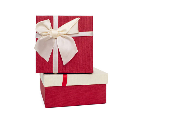 白い背景にリボンと弓を持つ2つの白と赤のギフトボックス。誕生日や伝統的な休日のための贈り物。一番上に立っている二つのギフトボックス - 写真・画像