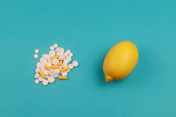 Close up of lemon and pills isolated on blue background. Top view. Cold prevention and treatment. Vitamin C - Fotografie, Obrázek