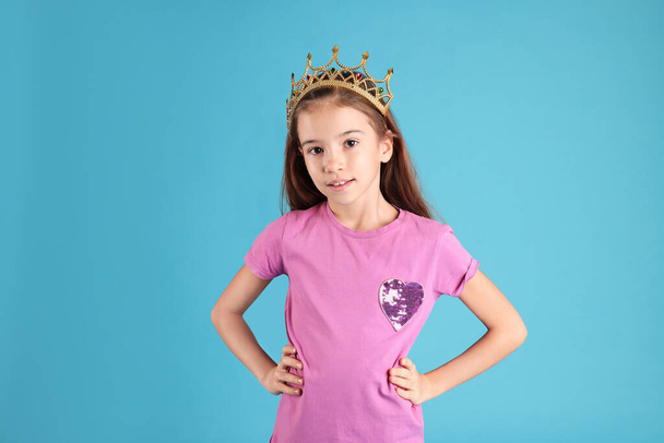 Cute girl in golden crown with gems on light blue background. Little princess - Foto, Imagen