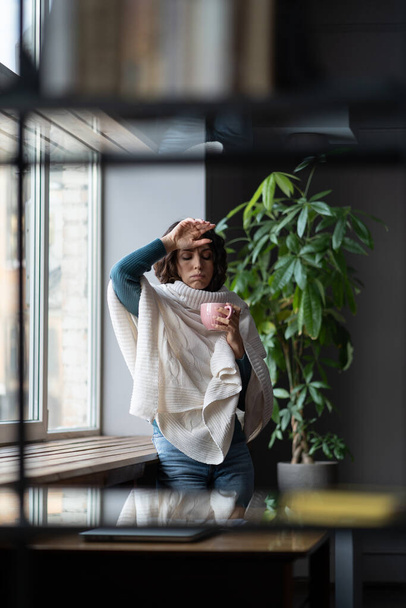 Ανθυγιεινά αδιάθετη επιχειρηματίας που έχει πυρετό αγγίζοντας το μέτωπο, ενώ πίνοντας ζεστό τσάι στο γραφείο - Φωτογραφία, εικόνα