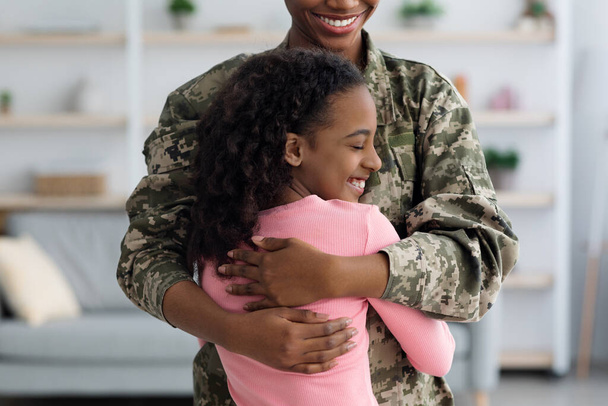 Κοντινό πλάνο της Αφροαμερικάνας που αγκαλιάζει τον πατέρα της στρατιώτη. - Φωτογραφία, εικόνα