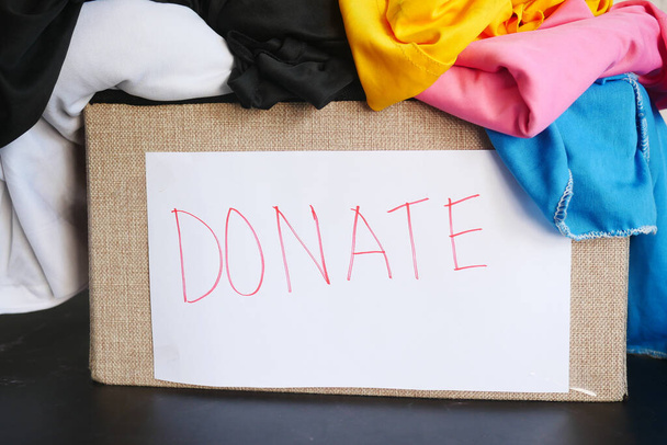 Caja de donaciones con ropa de donación en una mesa de madera . - Foto, imagen