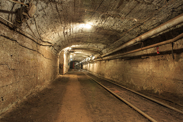 Smalle spoorweg in de ondergrondse mijnhorizon. Technologieën van de mijnbouw van mineralen door de ondergrondse methode. Ondergrondse mijn voor mijnerts - Foto, afbeelding