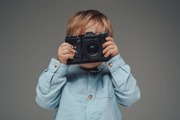 Piccolo fotografo bambino con fotocamera isolata su grigio - Foto, immagini
