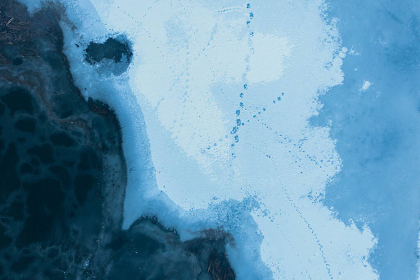 Texture di ghiaccio e neve sul fiume invernale ghiacciato: vista dall'alto drone shot. - Foto, immagini