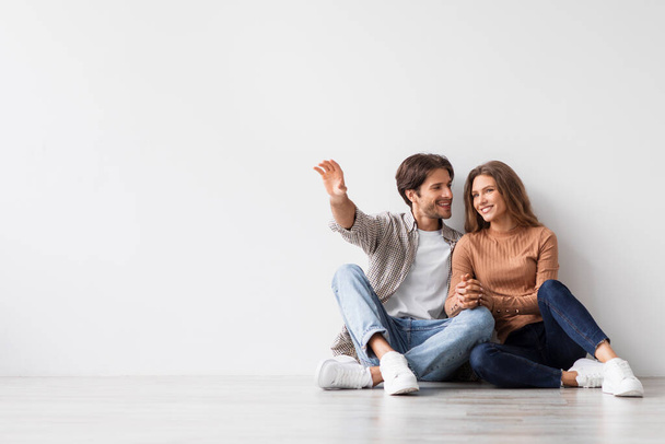 Satisfied millennial caucasian guy and lady planning future interior, dream, sit on floor - Photo, image
