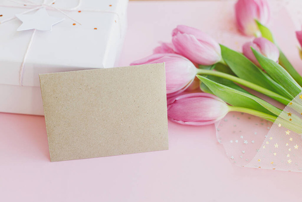 Lege wenskaart, roze tulpenboeket en geschenkdoos op roze achtergrond. Wenskaart template met ruimte voor tekst. Gelukkige vrouwendag. Fijne Moederdag. 8 maart - Foto, afbeelding