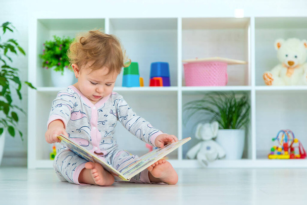 Baby is looking at a book. Selective focus. Child. - Фото, изображение