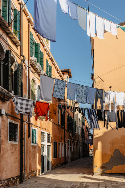 Laundry, що висить на типовому венеціанському фасаді, Italy. Вузька вулиця з барвистими будівлями і одягом сухо на мотузці, Venice.Чистий одяг сушиться на відкритому повітрі в невеликому сквотер.Міський спосіб життя, міська сцена - Фото, зображення