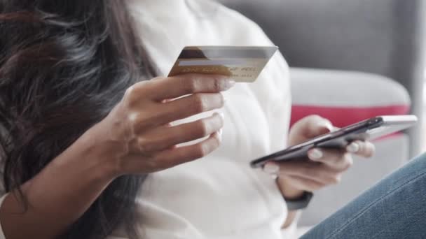 Zblízka ruce mladé asijské žena zákazník drží kreditní kartu a smartphone sedí na pohovce doma. Ženy používající mobilní nákupní online obchody během pandemie COVID-19. - Záběry, video