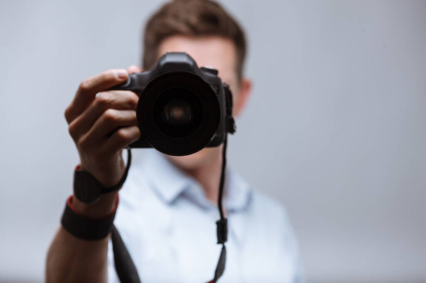 Fotógrafo segurando câmera dslr no fundo brilhante - Foto, Imagem