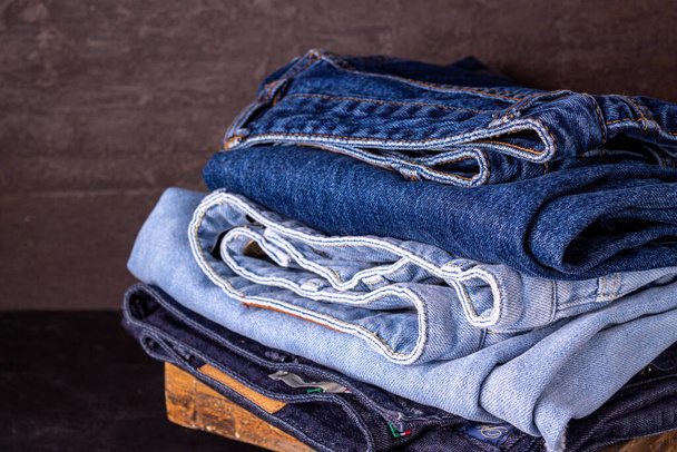 hromada džínových kalhot na hnědém pozadí - Fotografie, Obrázek