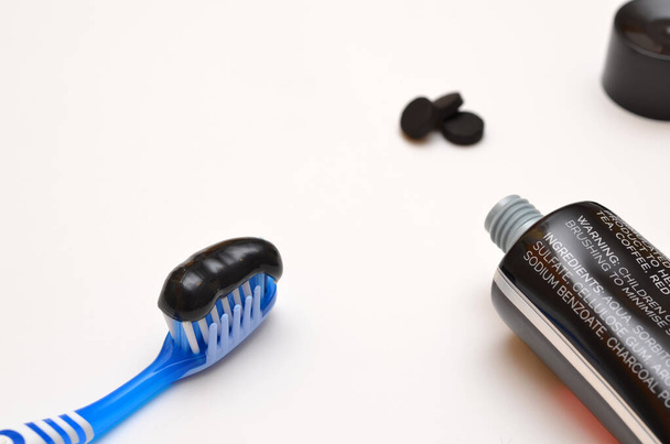 pasta de dientes negra con carbón activado y un tubo sobre un fondo blanco - Foto, Imagen