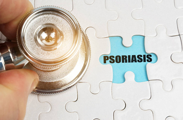 Medical concept. On puzzles a hand with a stethoscope, on a blue background the inscription - PSORIASIS - Photo, Image