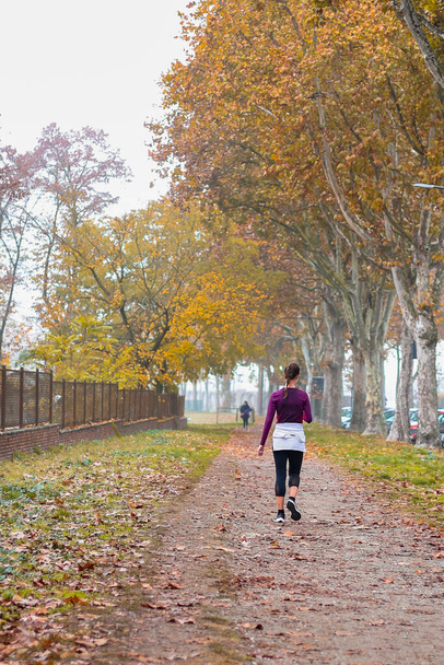 Sport in the autumn park. Woman running jogging on a autumn park path. Mock up and copy space. Day sport development. - Foto, afbeelding