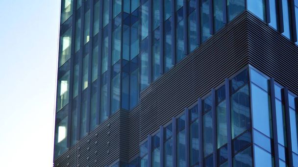 Modern şehrin iş bölgesindeki bina parçaları. Şehir merkezindeki yüksek katlı ofis binası. Tipik beton, cam ve çelikten modern mimari. - Fotoğraf, Görsel