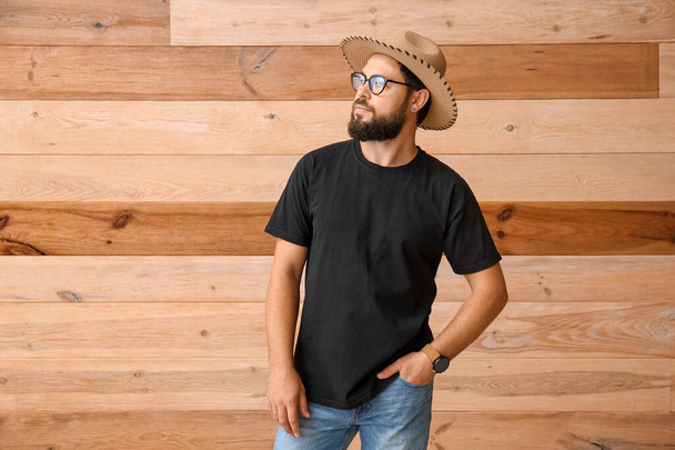 Jovem elegante em t-shirt preta em fundo de madeira - Foto, Imagem
