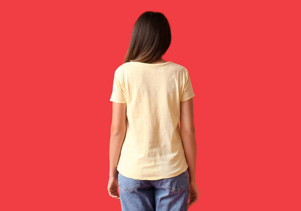 Mujer joven en camiseta en blanco sobre fondo de color, vista trasera - Foto, Imagen